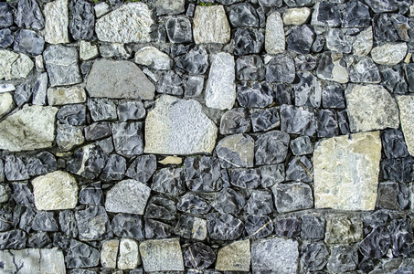 片段的旧砖墙与河石头纹理白色灰色，棕色，黑色，绿色，蓝色，石灰，黄橙栗色紫粉红色绿松石彩色背景，不同类型的石材马赛克表面
