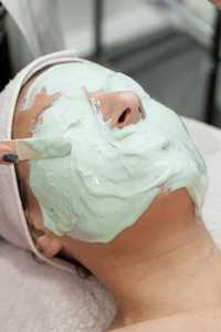 有吸引力的白种人妇女用海藻酸钠抗皱面膜洗脸海藻面膜的女孩带海藻