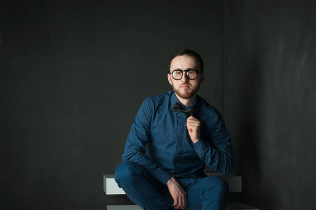 画室肖像，穿着一件蓝色的衬衫和牛仔裤的黑墙上背景年轻时髦的人