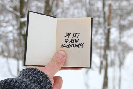 男子拿着一本书以题字说是向新的冒险的冬季森林背景