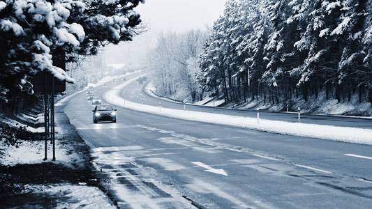 在有雪的冬季道路上的汽车。危险的汽车交通，在恶劣的天气