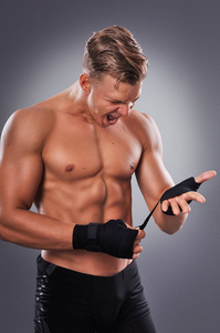 肌肉的战斗机准备战斗的手套和激励自己。拳击在灰色的背景上。健康的生活方式的概念