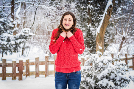 冬天。在雪背景笑的红毛衣的女孩