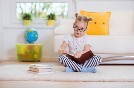 聪明的小女孩坐在一起的书在地板上的肖像