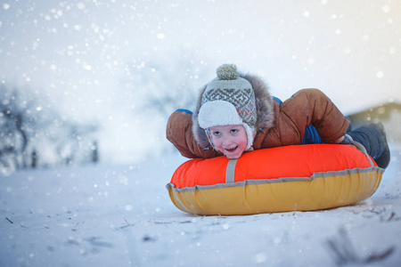 滑动与油管在雪 冬季 幸福概念的可爱男孩