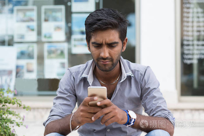 男子电话.拿着手机看短信的特写肖像生气印度男性户外隔离背景