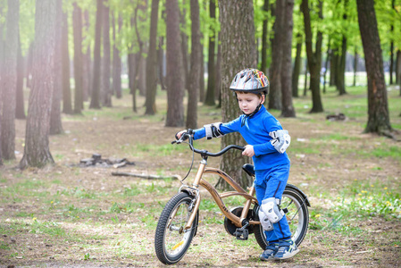 他的第一辆自行车在阳光灿烂的夏天的一天，在户外玩的快乐可爱的金发孩子男孩。孩子做运动。积极的休闲活动为儿童的。戴安全头盔。是微笑