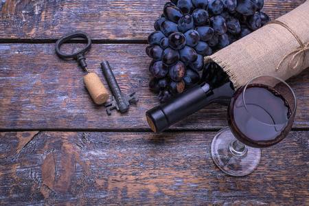 红酒一瓶 软木 瓶螺杆和一套产品奶酪 葡萄 坚果 橄榄 无花果上一块木板，在背景