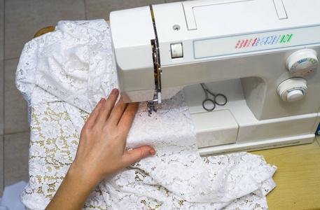 女人的手在缝纫机上工作。黑色和白色