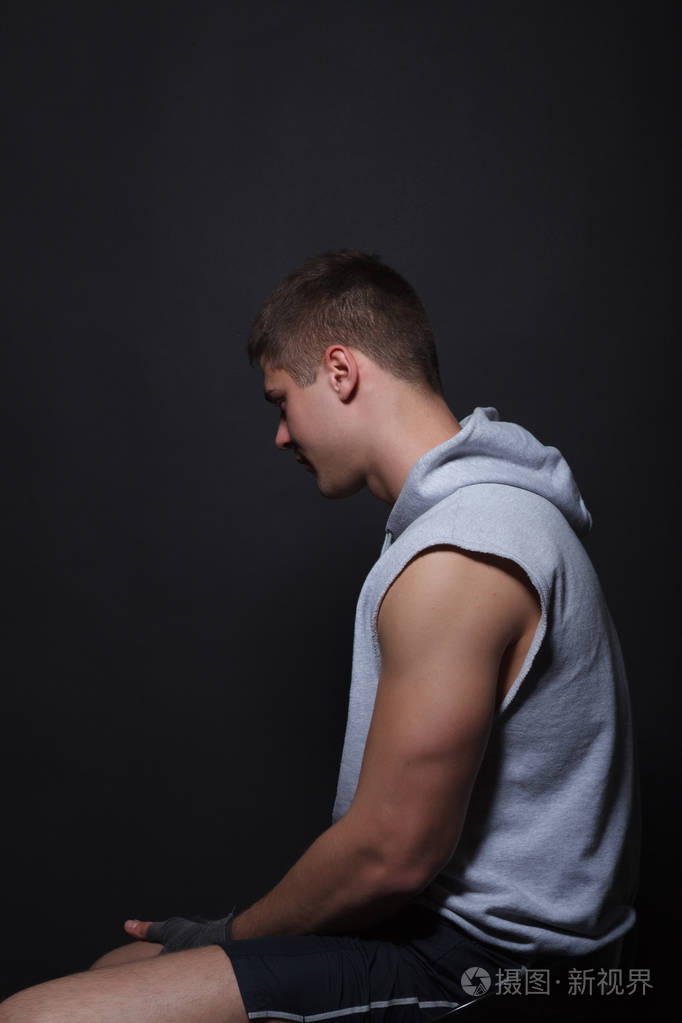 坐在椅子上一个黑色的背景侧身到相机上的肌肉战斗机