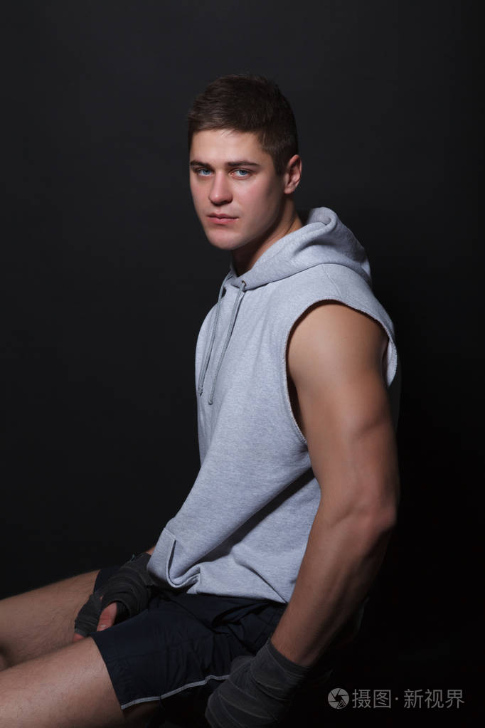 坐在椅子上一个黑色的背景侧身到相机上的肌肉战斗机