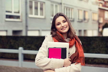 自信的年轻女孩业务女人抱着书孤立城市景观室外背景灰色背景,手里拿