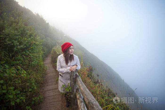 年轻的女子在峭壁上，俯瞰群山