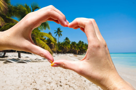 让心的形状，在海滩上的手。热带旅游胜地。度假概念。夏季假期。旅游
