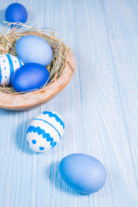 在蓝色木背景木碗的复活节彩蛋