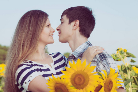 对年轻的夫妇站在一起在一个字段中的向日葵的肖像