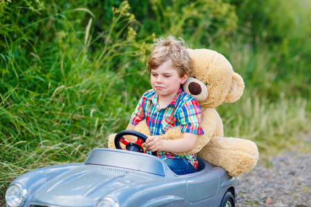 开车的大玩具和一只熊,在户外的小小孩男孩照片