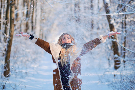 金发碧眼的年轻女人站在降雪冬季森林