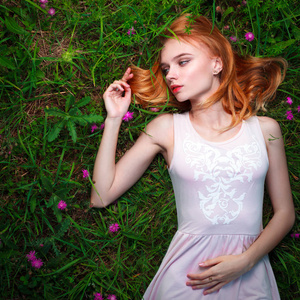 年轻漂亮的女人躺在草地上