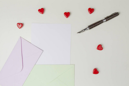 信封 消息 笔和小红心白色桌子上。给你的情书，情人节概念