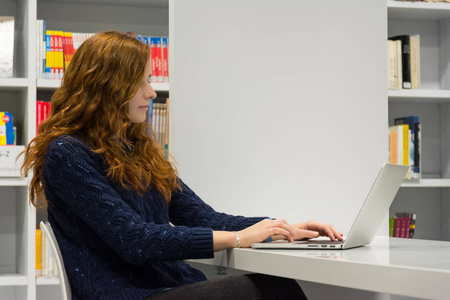 美丽的智能大学女孩在白色模式下使用笔记本电脑
