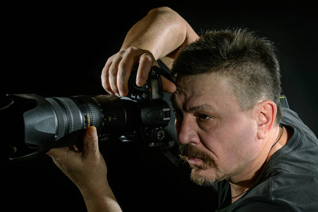 人像摄影师用相机在黑色背景上照片