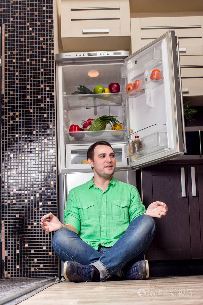年轻人坐在冰箱前