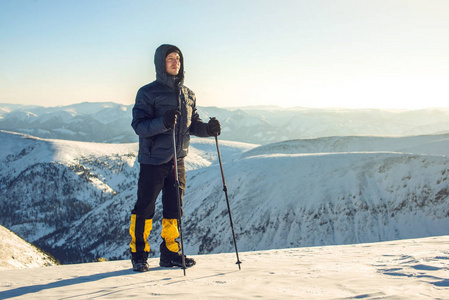 男子徒步旅行者站在白雪皑皑的山峰上日落