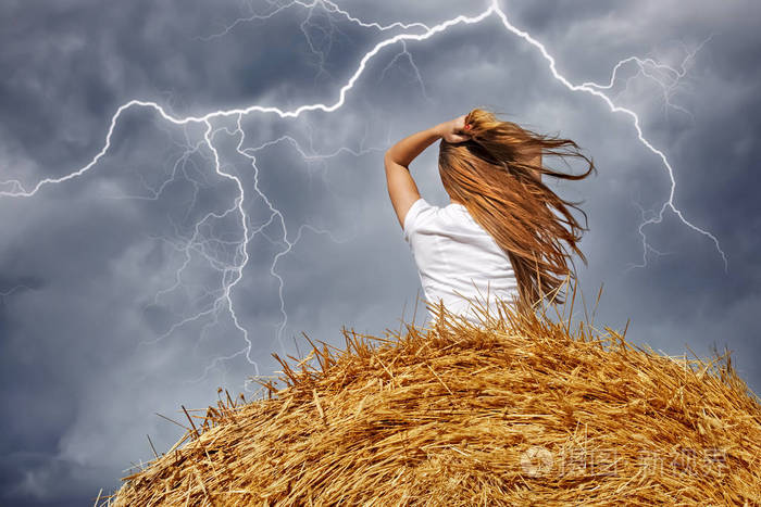 暴风雨和闪电中干草堆上的女孩