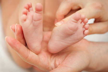 小小的脚的新出生的婴儿在她妈妈的手举行