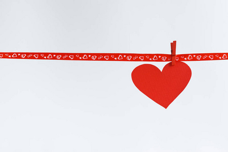 红纸心挂在白色背景上的红丝带。概念的情人节