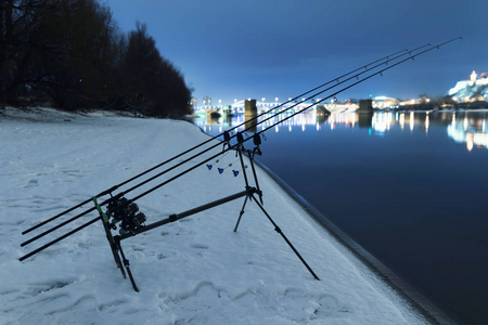鲤鱼纺纱卷轴钓鱼竿在冬夜。夜间垂钓