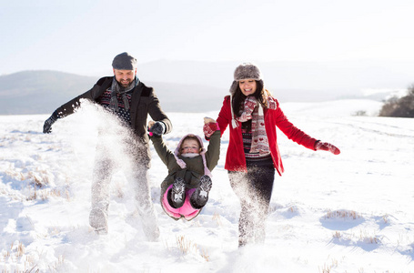 父亲和母亲带着他们的女儿，在雪地里玩