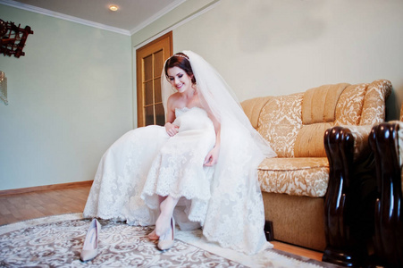 坐在床上的黑发新娘穿她的婚礼鞋子