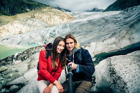 年轻夫妇徒步旅行在瑞士的阿尔卑斯山，以自拍照