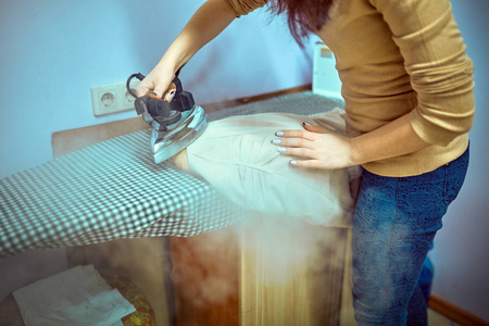 熨烫衣服熨烫板上的女人的特写图片