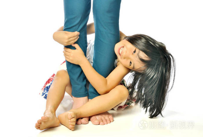 亚洲小女孩抱着妈妈的腿和玩