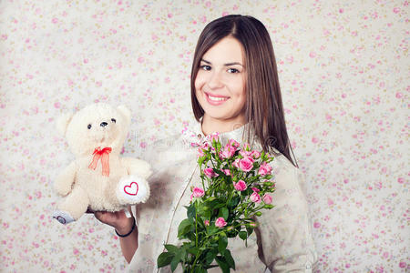 带着玫瑰花和玩具熊的漂亮年轻女子