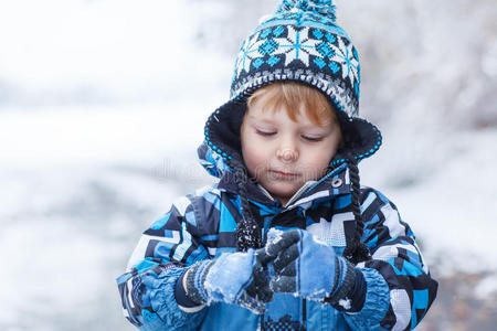 可爱的蹒跚学步的小男孩在冬天玩雪