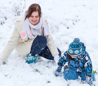 妈妈和蹒跚学步的男孩在冬天玩雪