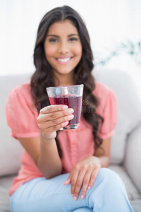 微笑可爱的黑发女人坐在沙发上拿着一杯果汁