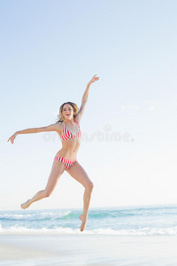 美丽的金发女人在沙滩上跳