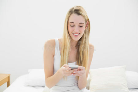 满足于金发女人坐在智能手机上发短信