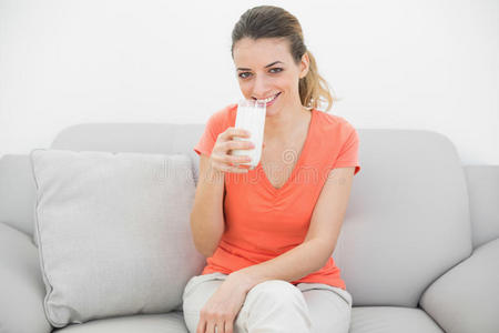 心满意足的女人拿着一杯牛奶在镜头前愉快地微笑