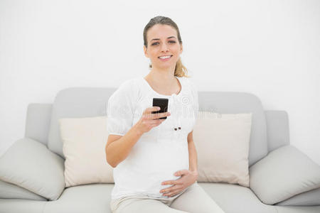 可爱孕妇拿着智能手机对着镜头开心地笑