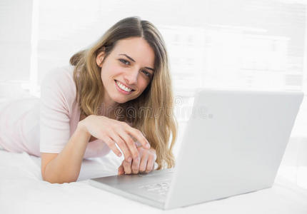 微笑的年轻女子躺在笔记本电脑前
