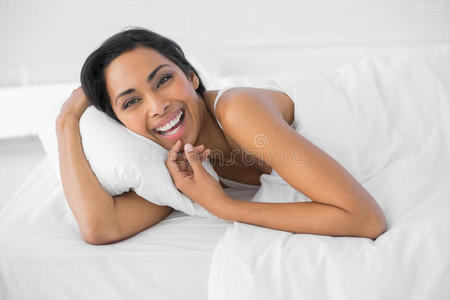 满足的笑女人躺在床上的被子下面