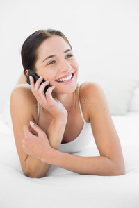 微笑的女人在床上用手机