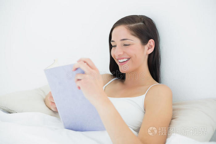 微笑的女人在床上看书