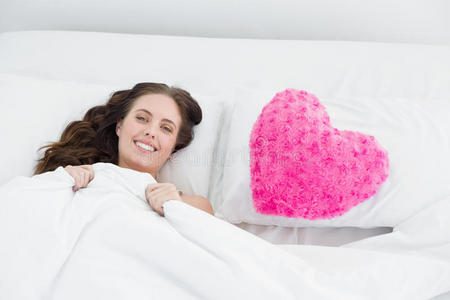 微笑的女人躺在床上，带着心形枕头套